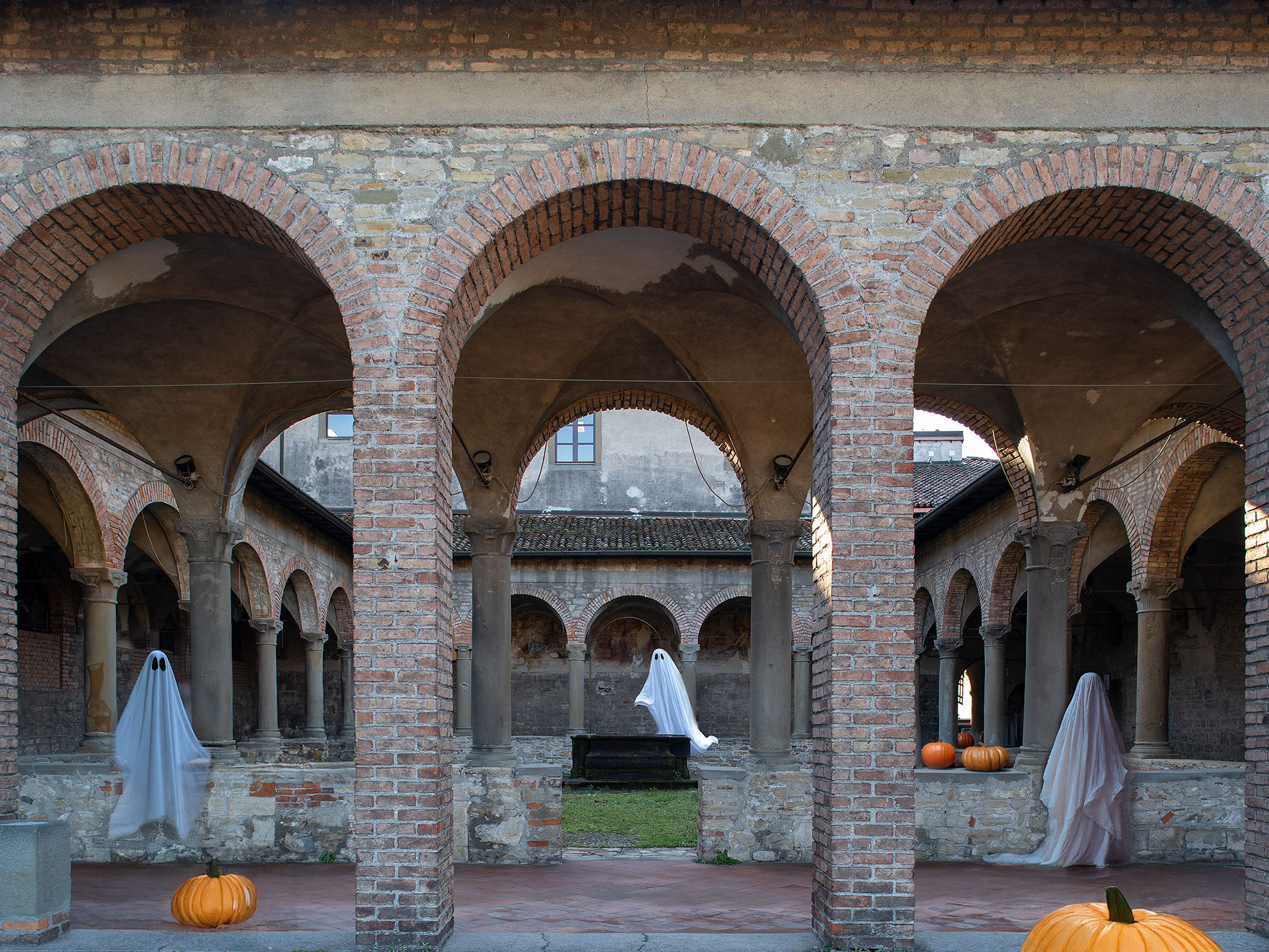 Il chiostro di un convento con tre fantasmi e zucche di halloween